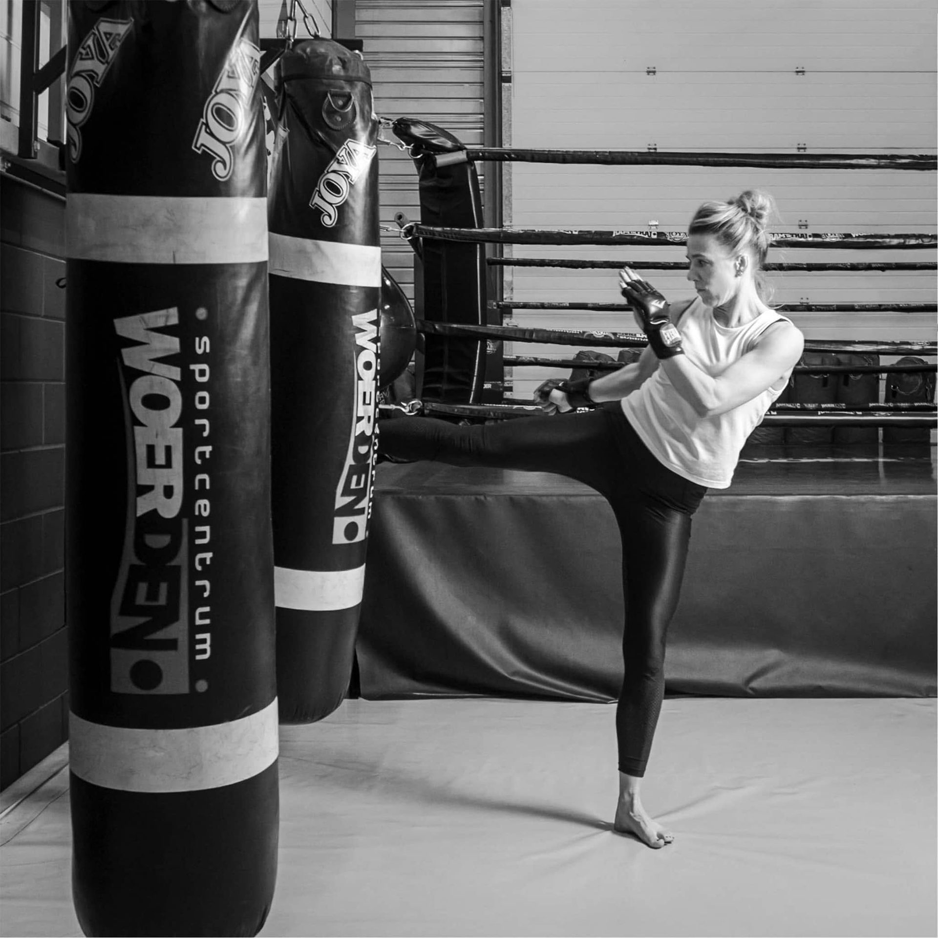 Hoge trap tijdens kickbokstraining in zwart-wit